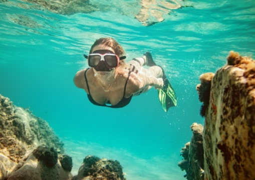 Cliente sumergiéndose en las cristalinas aguas del mar caribe con gafas de buceo en Isla Mujeres