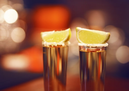 Two tequila-filled shot glasses with salt and lime on top in isla Mujeres